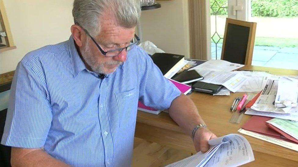 John Williams reading notes at a desk with paper work spread around