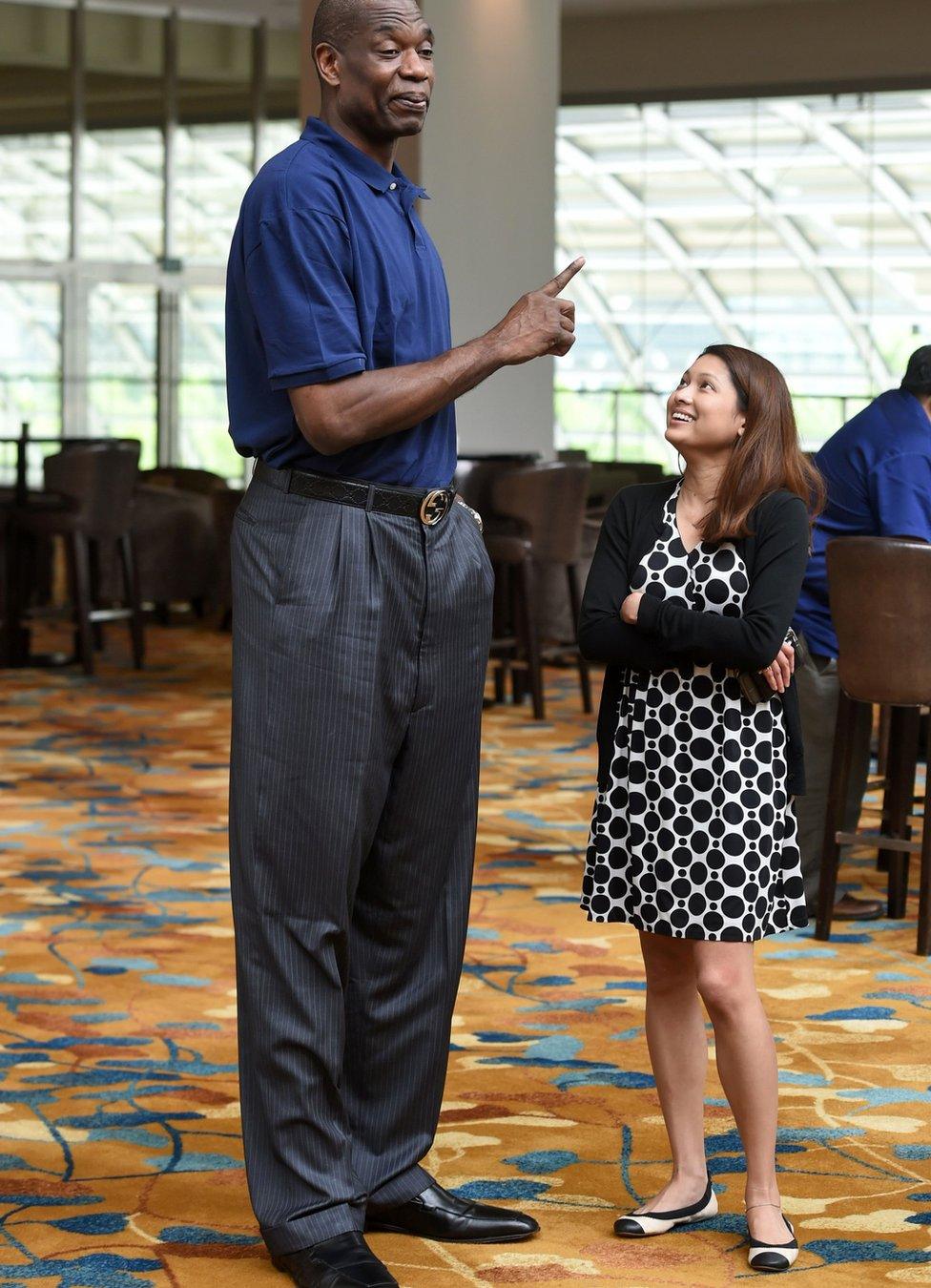 Retired professional basketball player Dikembe Mutombo (L) stands next to Sheila Rasu (R), a communication officer for NBA Asia after a media roundtable interview in Singapore - Tuesday 5 April 2016