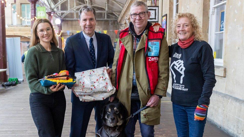 A group of people posing with a dog getting a parcel