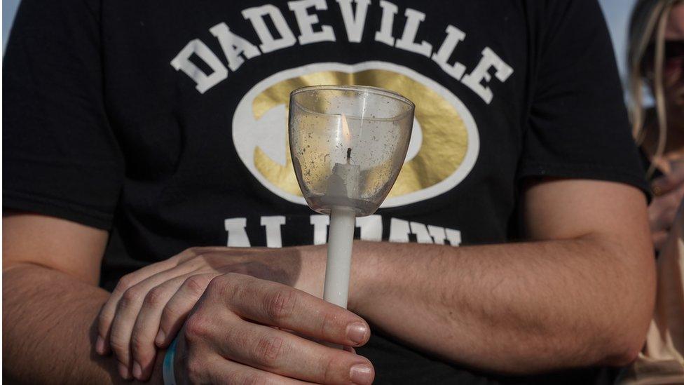 A person at a vigil holds a candle