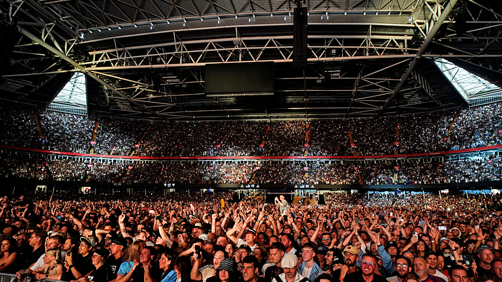 Packed stadium with a view from the stage, showing all the way to the back