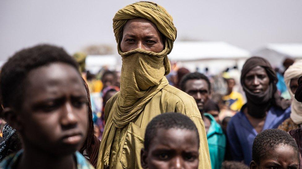 Refugees stand in Goudebou, a camp that welcomes more than 11,000 Malian refugees in northern Burkina Faso, on International Refugee Day on June 20, 2021.