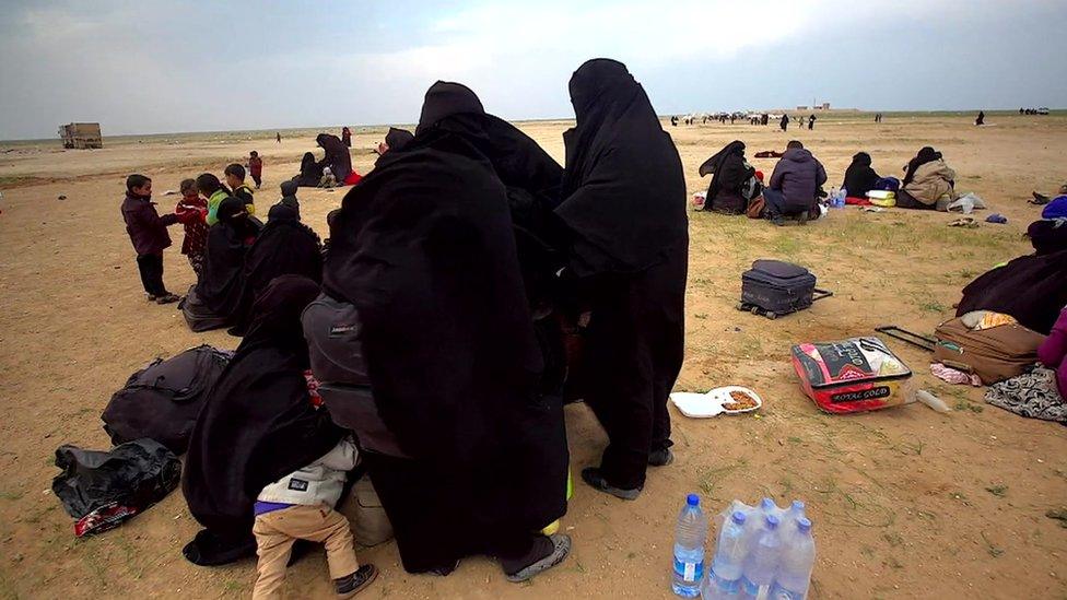 Children and women with their scattered belongings out in the open