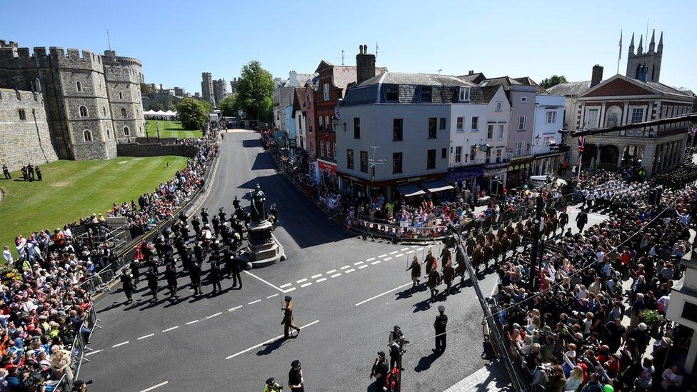 Police officers and members of the public watch as military personnel rehearse their part in the procession