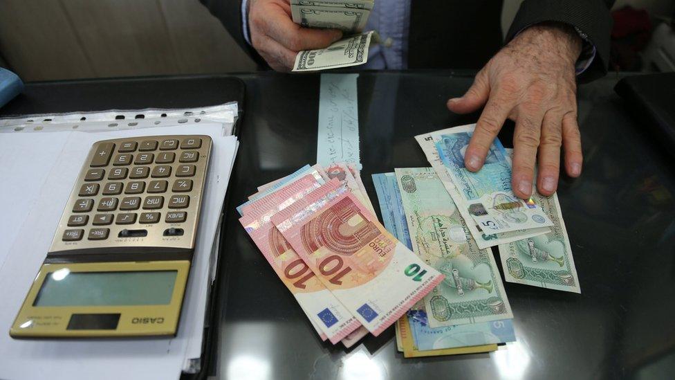 A money changer holds US dollar bills at Tehran's Grand Bazaar, Iran (14 October 2017)