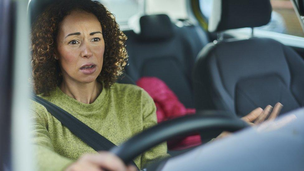 woman sat in car looking confused