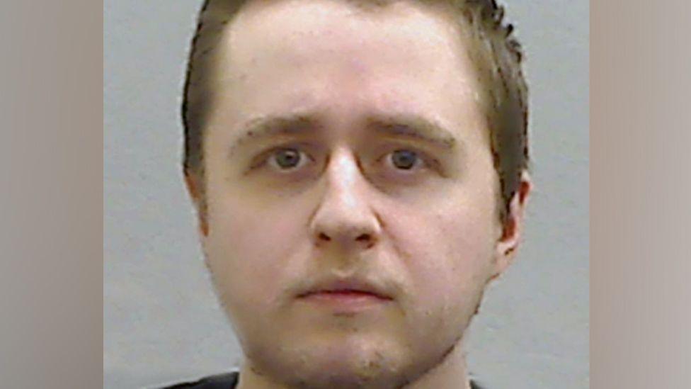 A police mugshot of Alexander McCartney, who has short, brown hair.