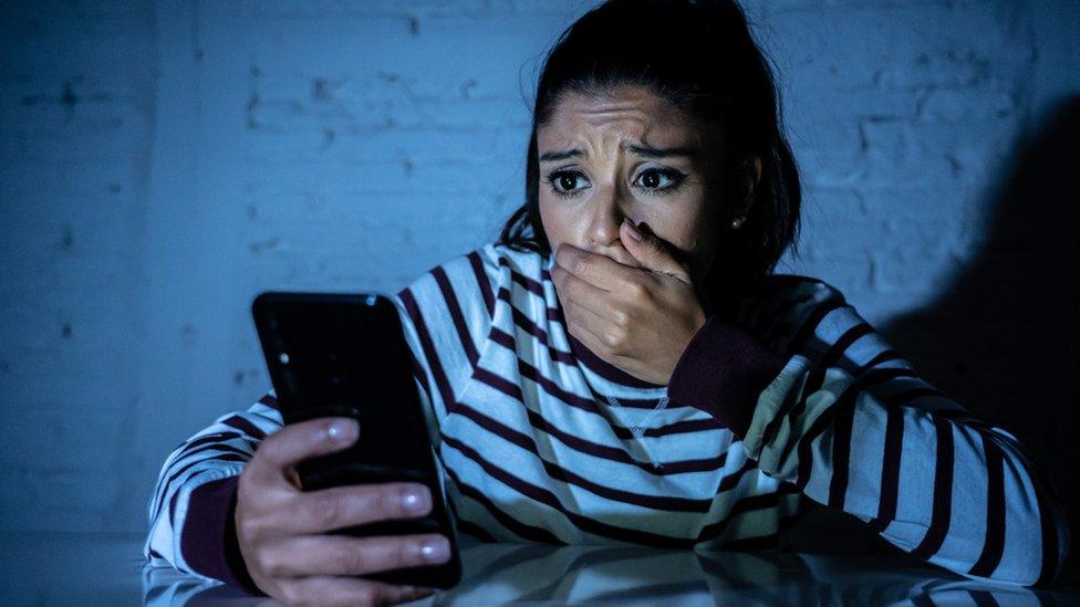 Stock image of a woman looking at her phone in shock.