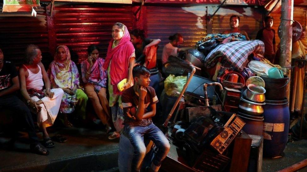 Local residents sit on the street with their belongings during the fire