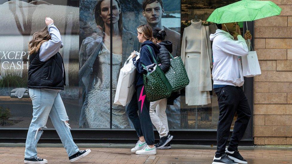 Shoppers carry bags in Walnut Creek, California, US, on Wednesday, Dec. 20, 2023. US retail sales unexpectedly picked up in November as lower gasoline prices allowed consumers to spend more to kick off the holiday shopping season.