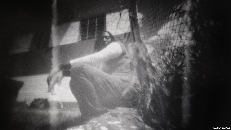 A woman leans against a fence