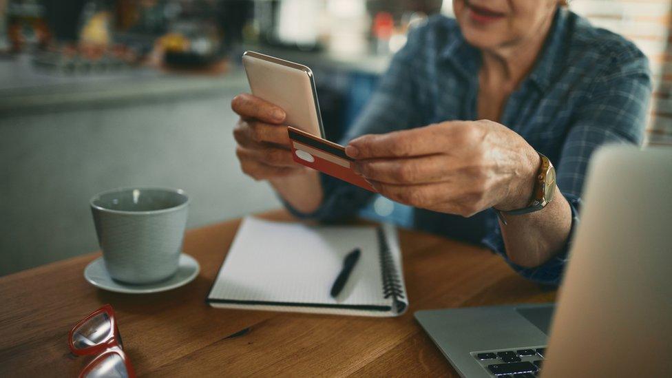 Woman at laptop with credit card and phone