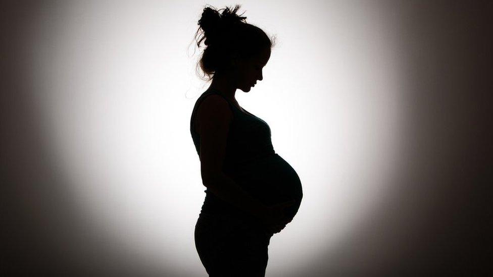 The outline of a pregnant woman in shadow