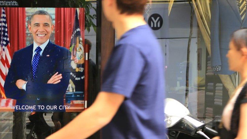 A Vietnamese couple pass a poster of U.S President Barack Obama with footnote read "Welcome to our city"