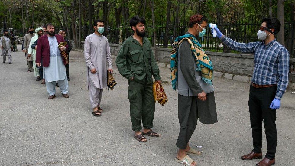 A health worker checks the body temperature of devotees before Friday prayers on the first day of Ramadan at Wazir Akbar Khan mosque in Kabul on April 24, 2020