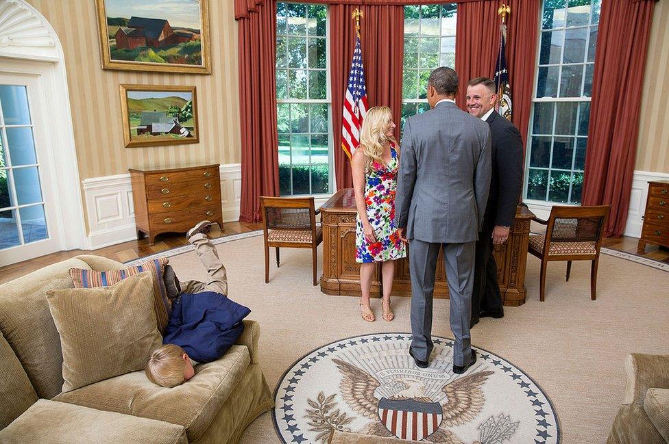 A young boy face-planting himself onto the sofa in the Oval Office