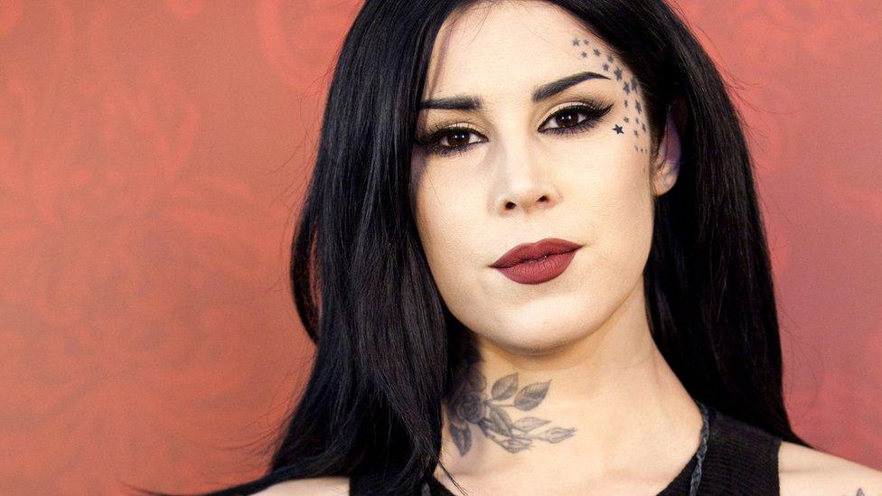 Kat Von D headshot at Sephora event. Pictured with dark red lips against red flock background.