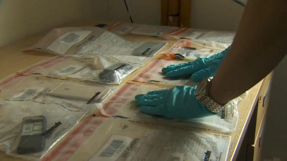 Office wearing gloves sorting evidence in plastic bags