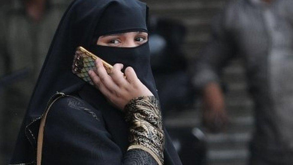 A Muslim woman talks on her phone as she walks in the old Delhi city area, India, 22 August 2017