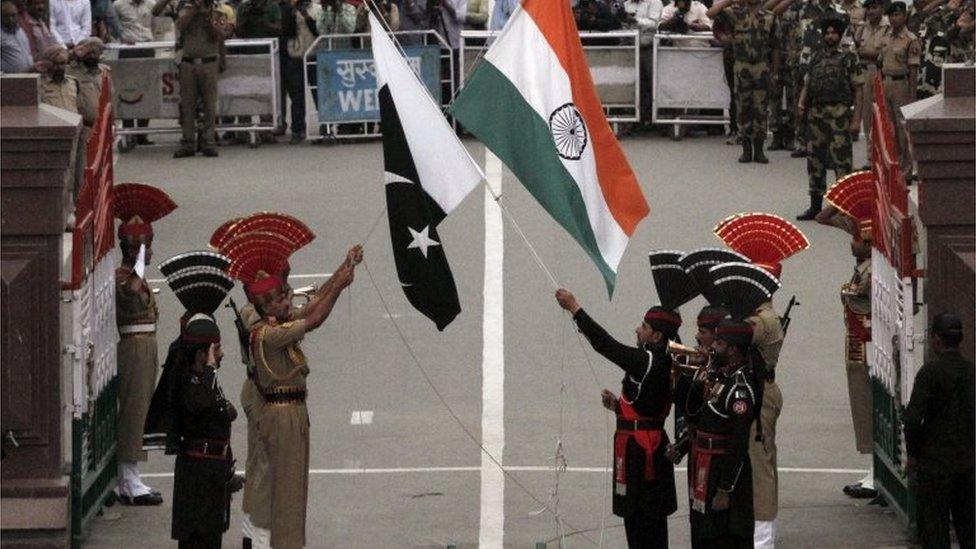 Pakistani rangers (wearing black uniforms) and Indian Border Security Force (BSF) officers lower their national flags during a daily parade at the Pakistan-India joint check-post at Wagah border near Lahore, Pakistan