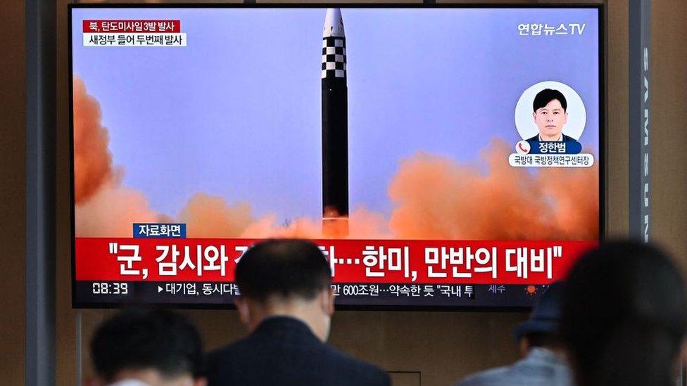 People watch a television screen showing a news broadcast with file footage of a North Korean missile test, at a railway station in Seoul on May 25, 2022, after North Korea fired three ballistic missiles towards the Sea of Japan according to South Korea's military.