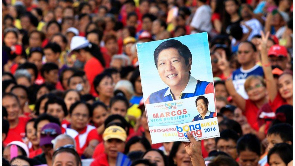 A supporter of Philippine vice-presidential candidate senator Ferdinand "BongBong" Marcos holds up a poster bearing an image of him, amid a crows at a "rally in Metro Manila on 2 May