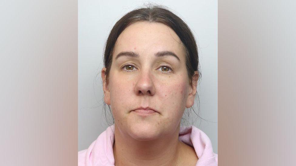 Lucy Connolly with brown hair tied back. She is wearing a pink top in a police custody photo