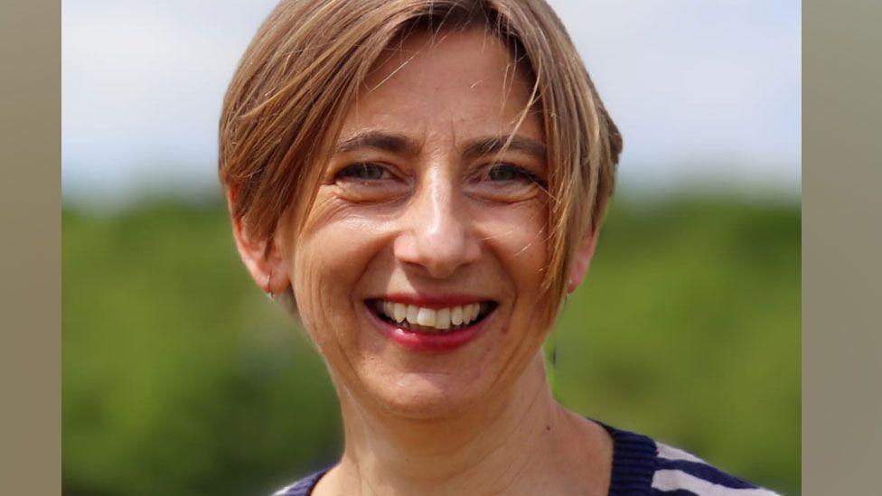 Elizabeth McWilliams wearing a blue and white striped top and looking at the camera