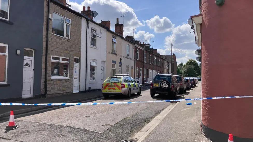 The police cordon on Wheeldon Street in Gainsborough. A police car can be seen parked on the street, which has terraced houses.