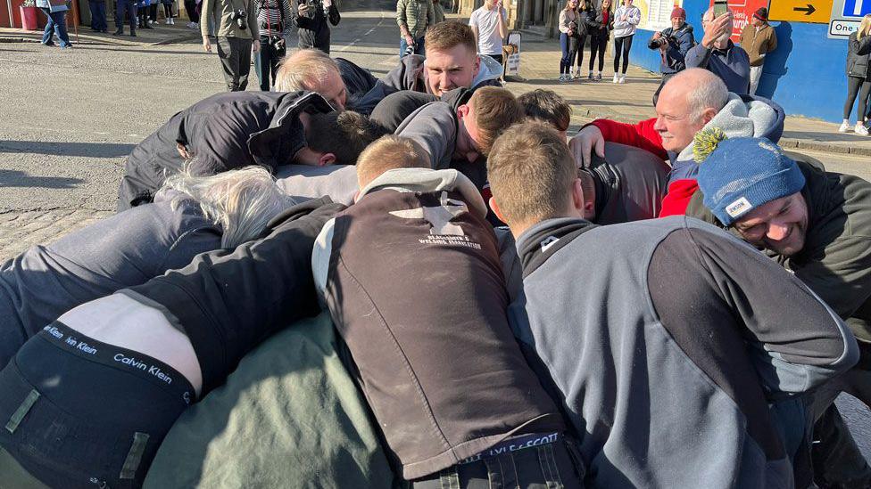 A group of men are in a scrum to get control of a leather ball in Jedburgh's handball game