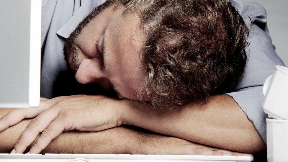 Man sleeping at his desk with his head on his keyboard