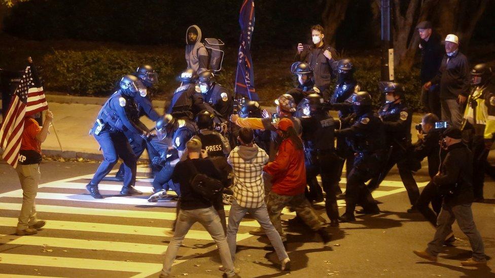 Law enforcement personnel detain a person as supporters of President Donald Trump clash with people opposing them on a street, in Washington DC