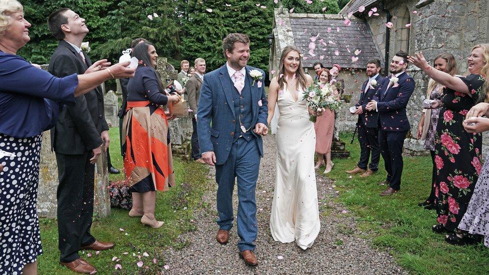 James Bone and Lucy Johnston are applauded by guests outside the church