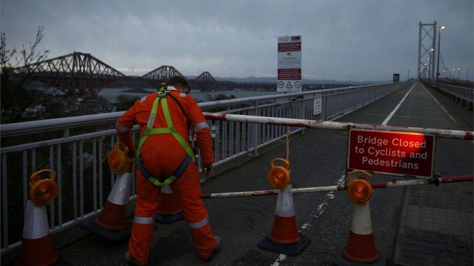 A workman closes a barrier at the Forth Road Bridge which is closed to traffic until the New Year due to structural faults