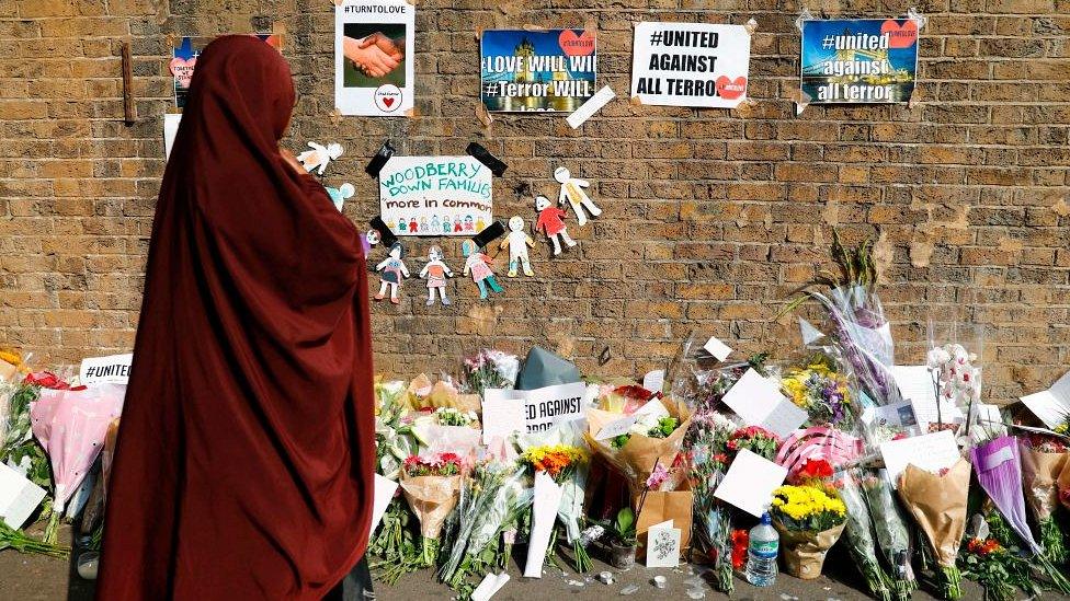 People stop to read tributes and look at flowers placed near the Finsbury Park mosque