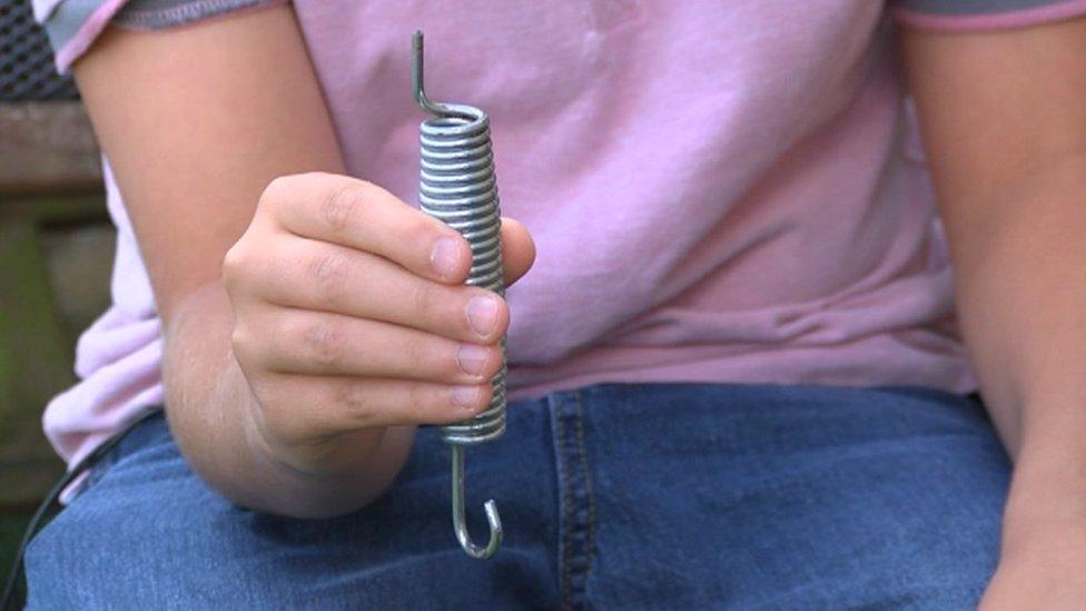 Child's hand holding a silver metal coil spring