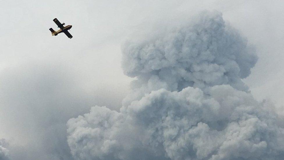 A firefighting plane passes smoke as it pulls up from the Zezere River after picking up water to put out forest fires in the area near Pedrógão Grande, June 18 2017.