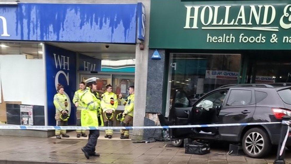 The car on the pavement, having crashed into the store