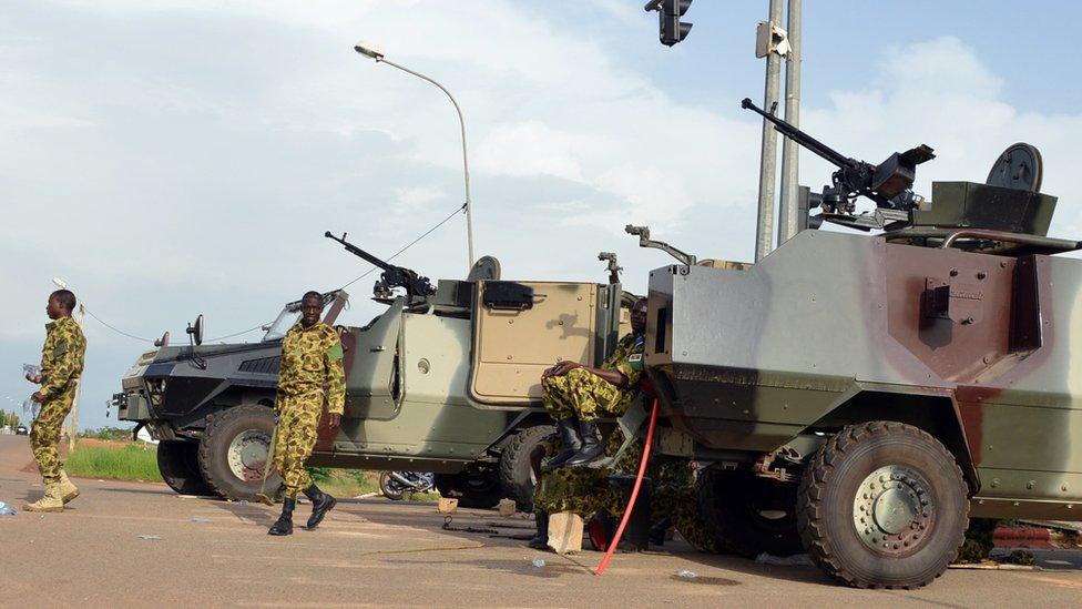 Soldiers stand next to vehicles outside the presidential palace in Ouagadougou