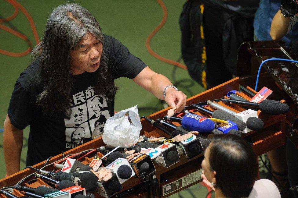 Pro-independence lawmaker Leung Kwok-hung (L), known as Long Hair, holds up a piece of lunchmeat as he argues with pro-Beijing lawmaker Priscilla Leung Mei-fun on 19 October 2016