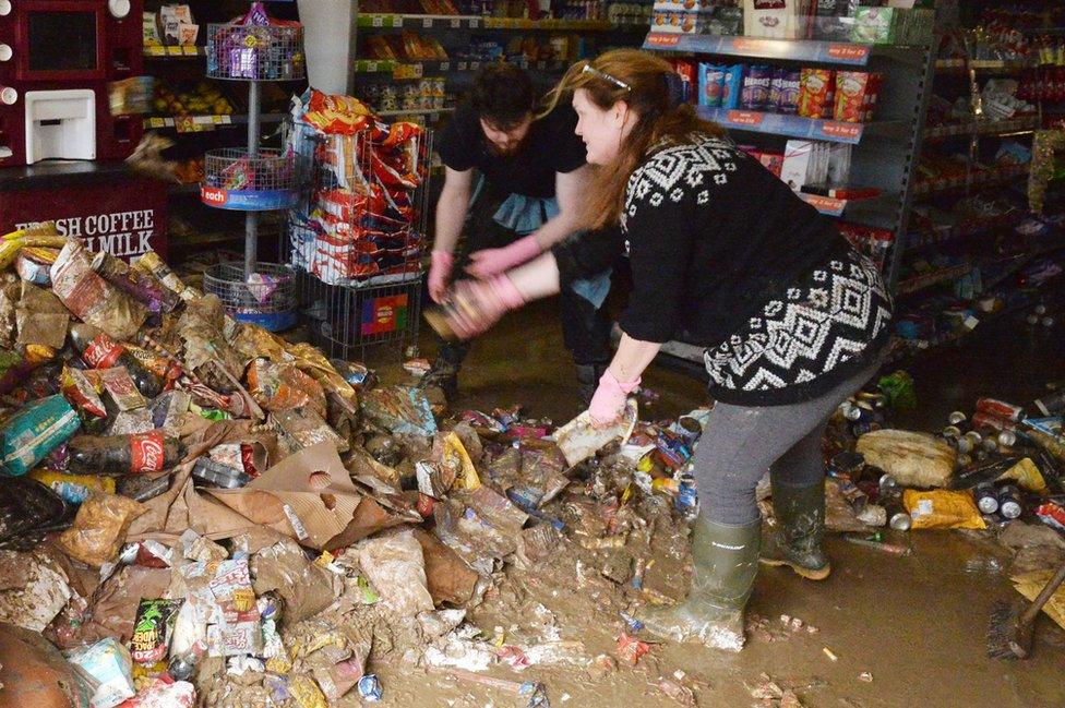 Shop workers in Cockermouth clean up the mess in the aftermath of the weekend's flooding