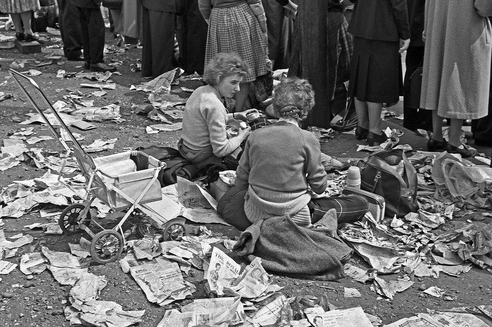 Two women enjoying a picnic amid newspapers on the ground, Royal Wedding