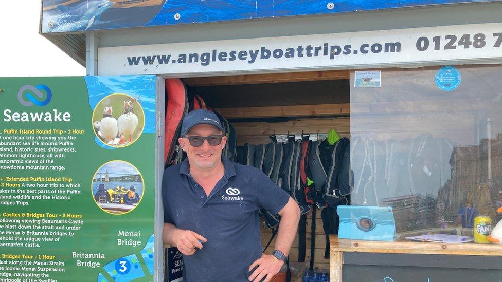 Man in front of Beaumaris boat trips stall