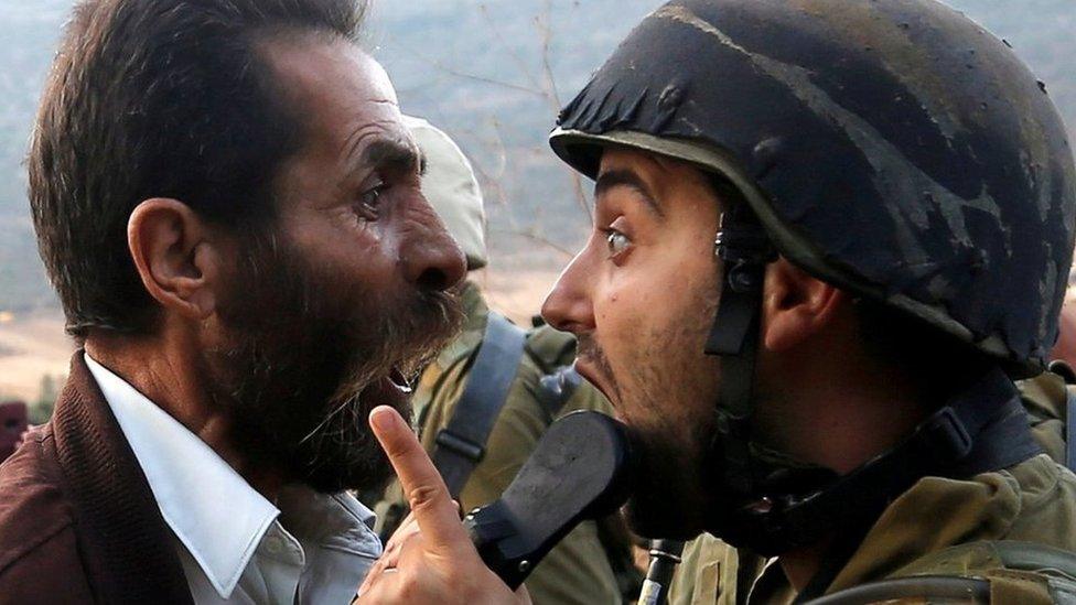 A Palestinian man and an Israeli soldier argue