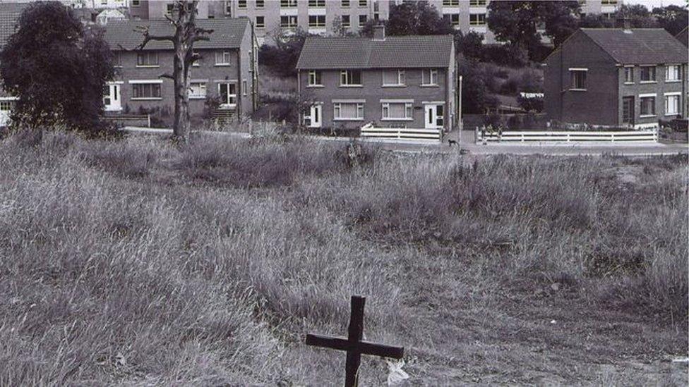 A wooden cross in a field in the Ballymurphy area