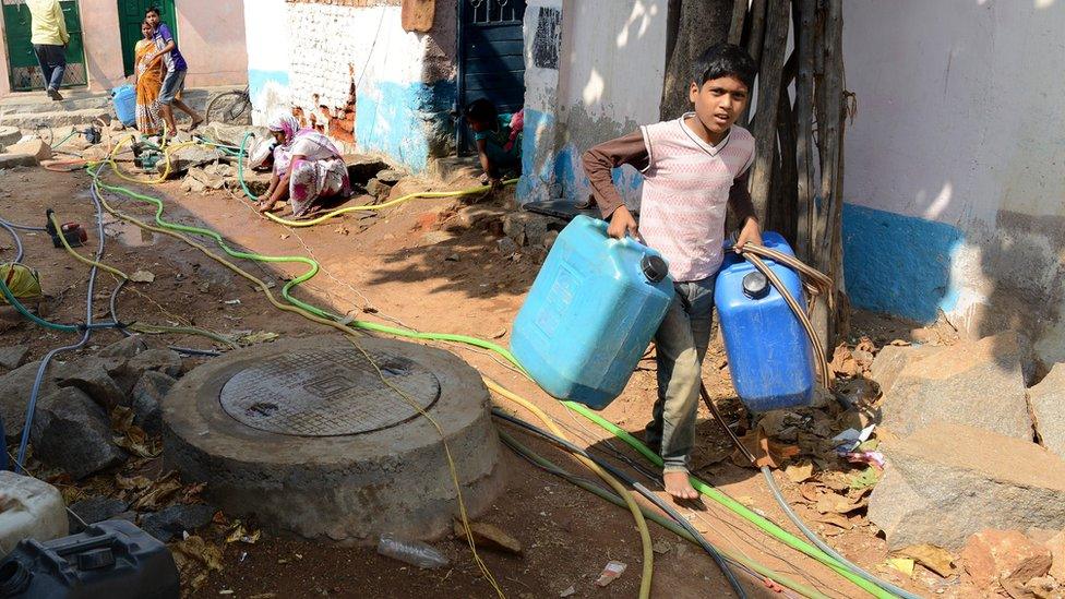 Boy filling water in jerry cans