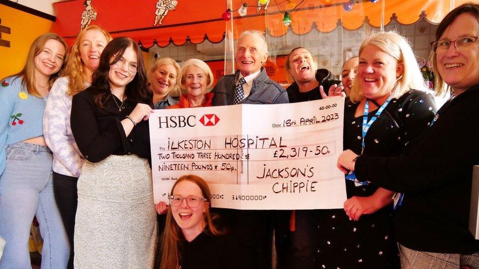 Dennis Jackson, hospital staff and chip shop staff holding a big cheque inside his former shop on Market Street