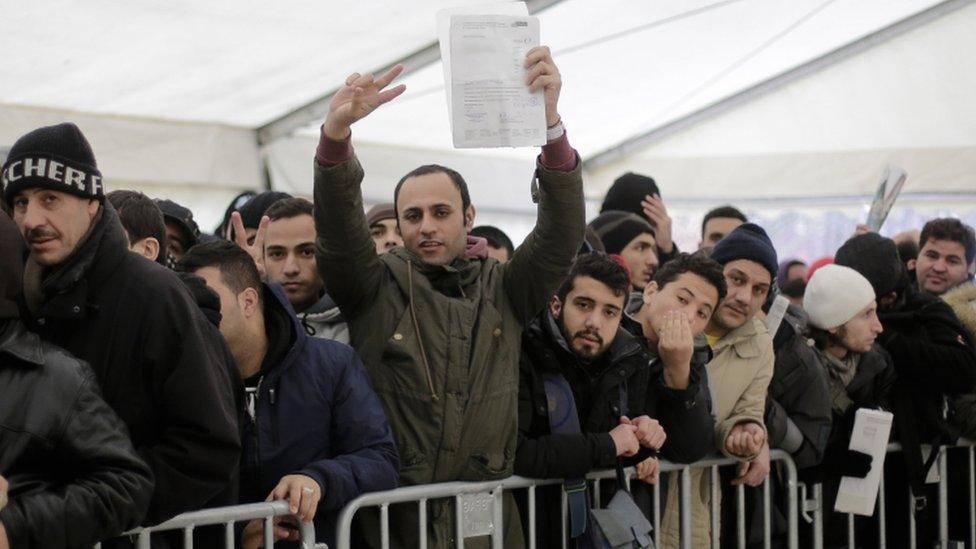 A migrant shows a document as he awaits registration in Germany