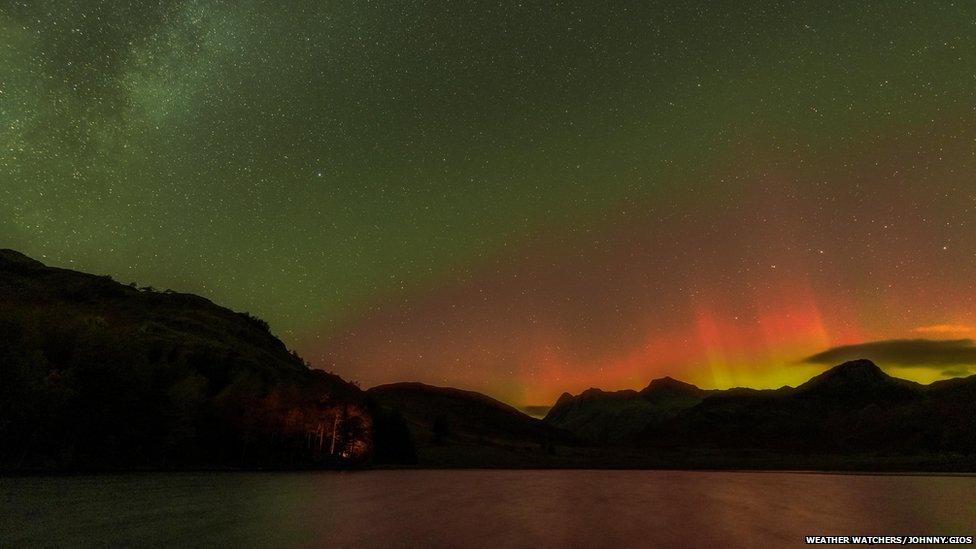 Orange and green skies in front of the hills of Blea Tarn in Cumbria.