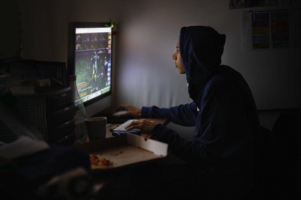 Boy sits in dark playing computer games